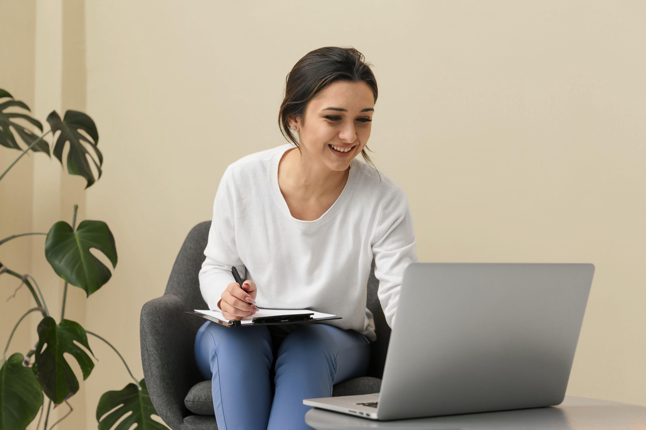Une femme prend des notes devant son ordinateur portable